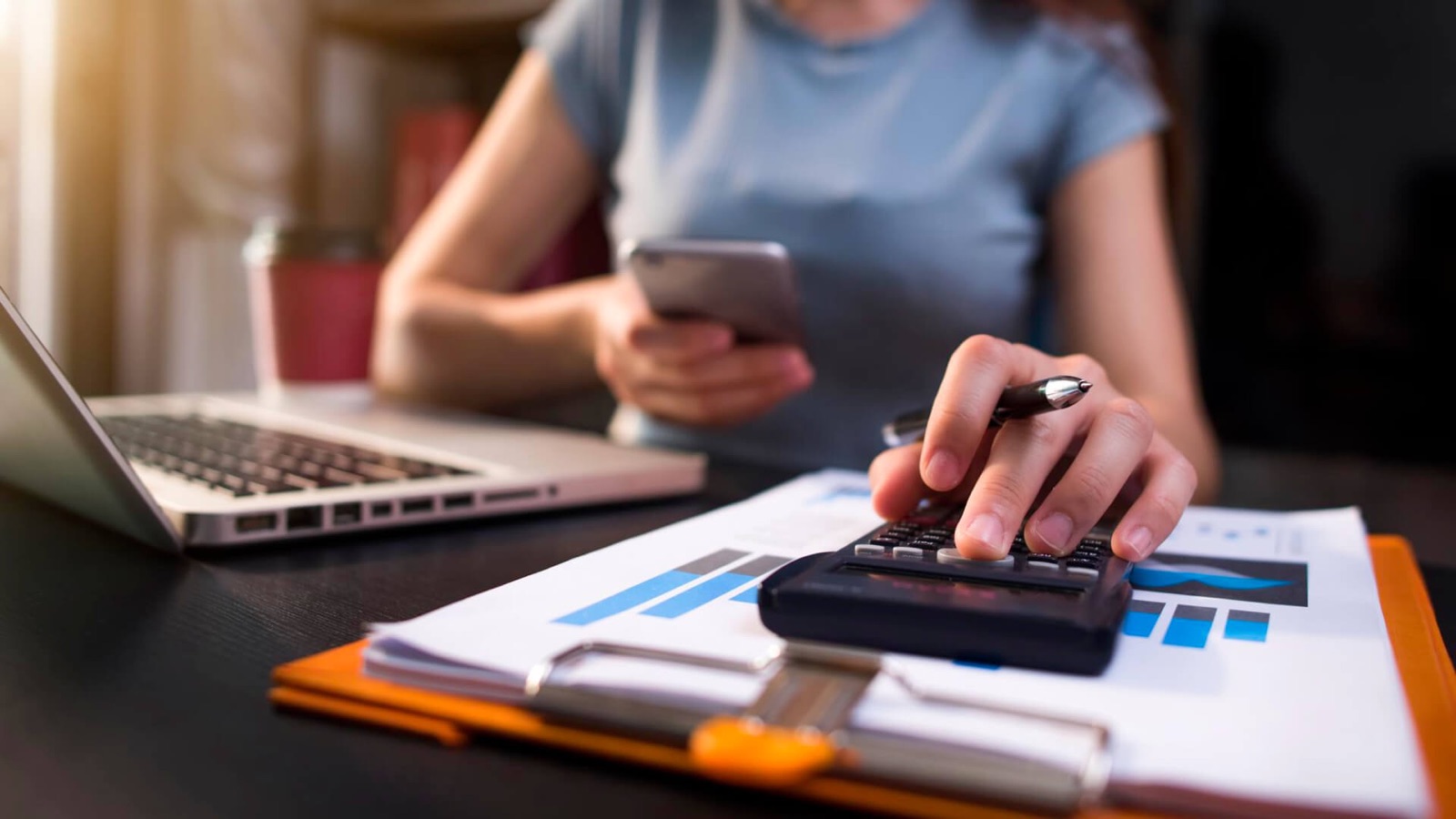 Persona revisando las ventas de su negocio con calculadora y celular